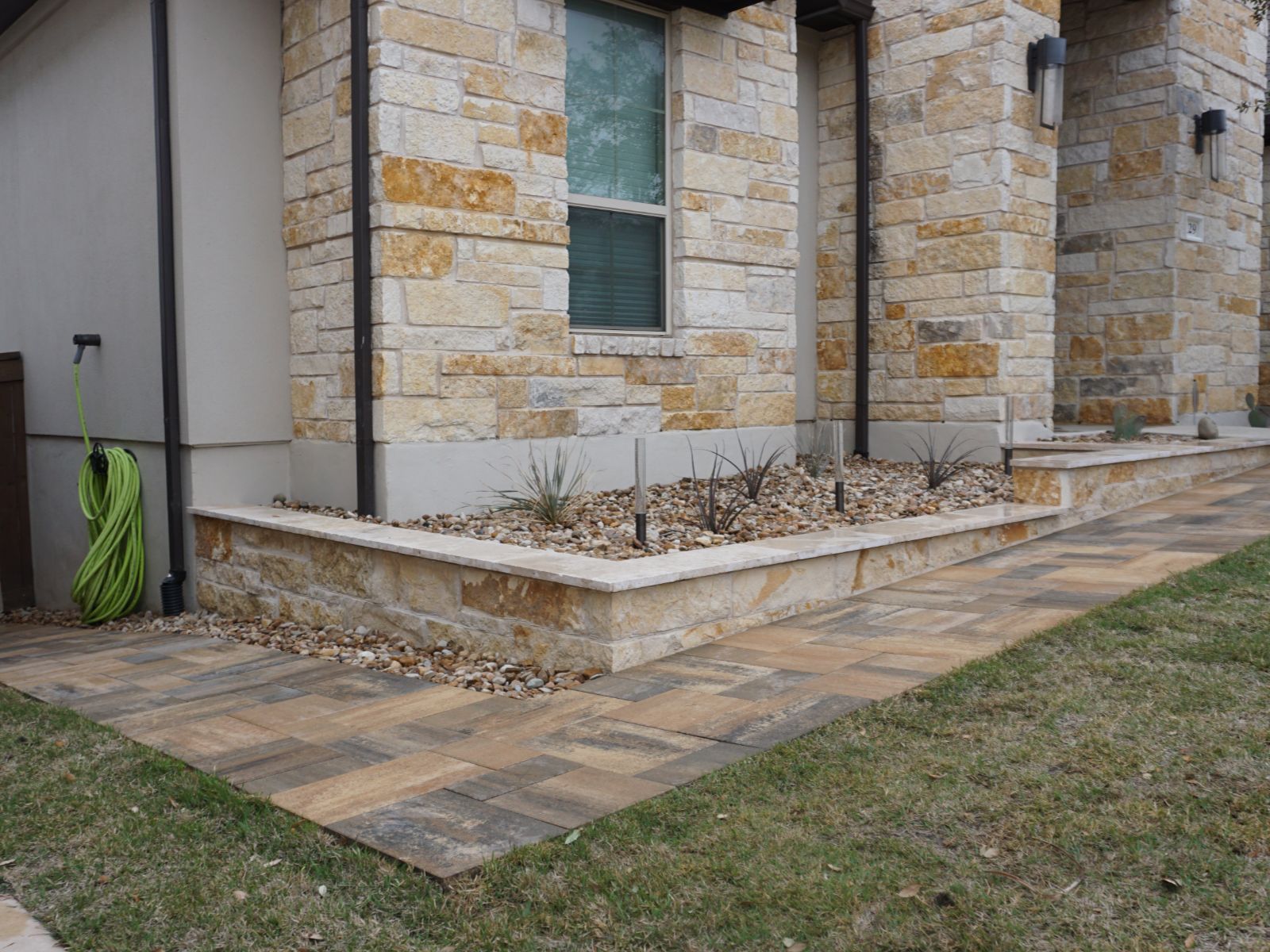 Front yard stone landscaping with walkway and raised garden bed along house exterior