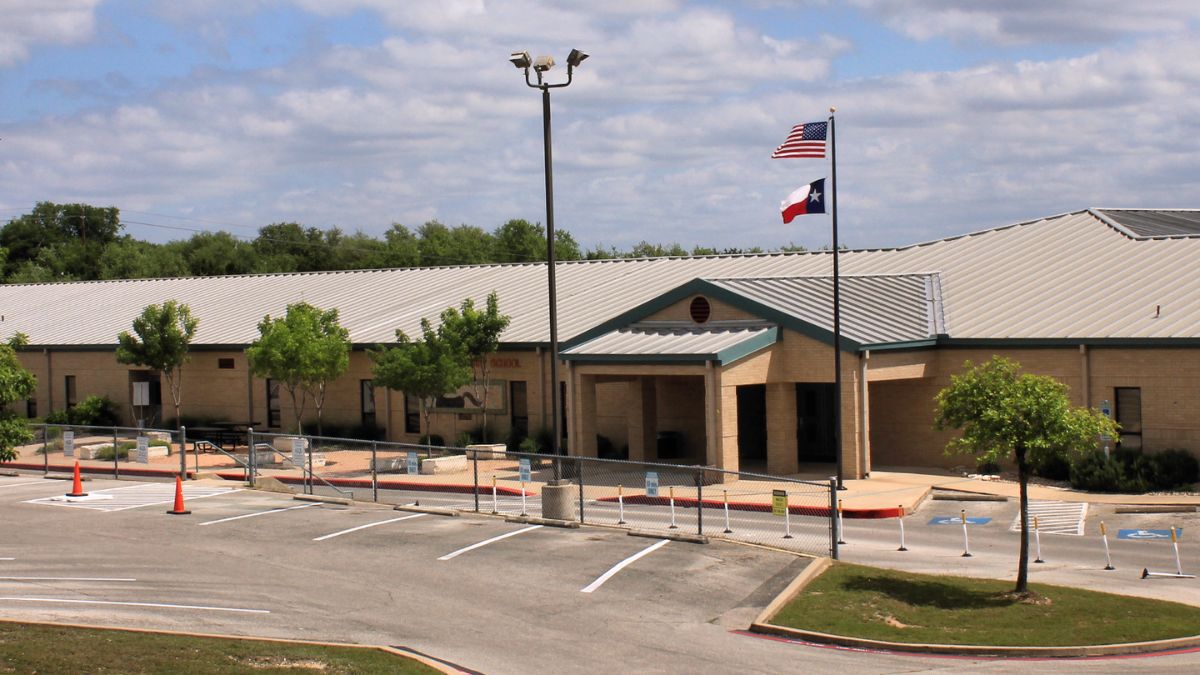 Exterior of a school building with American and Texas flags flying outside
