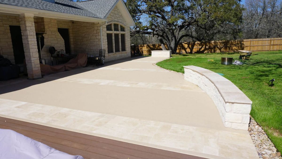Custom stone patio with curved seating wall in Austin, TX backyard