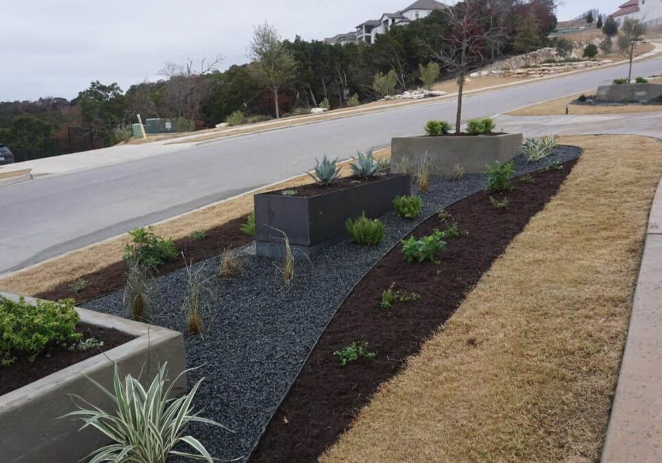 Contemporary street-facing landscape with raised planters and rock beds in Austin, TX