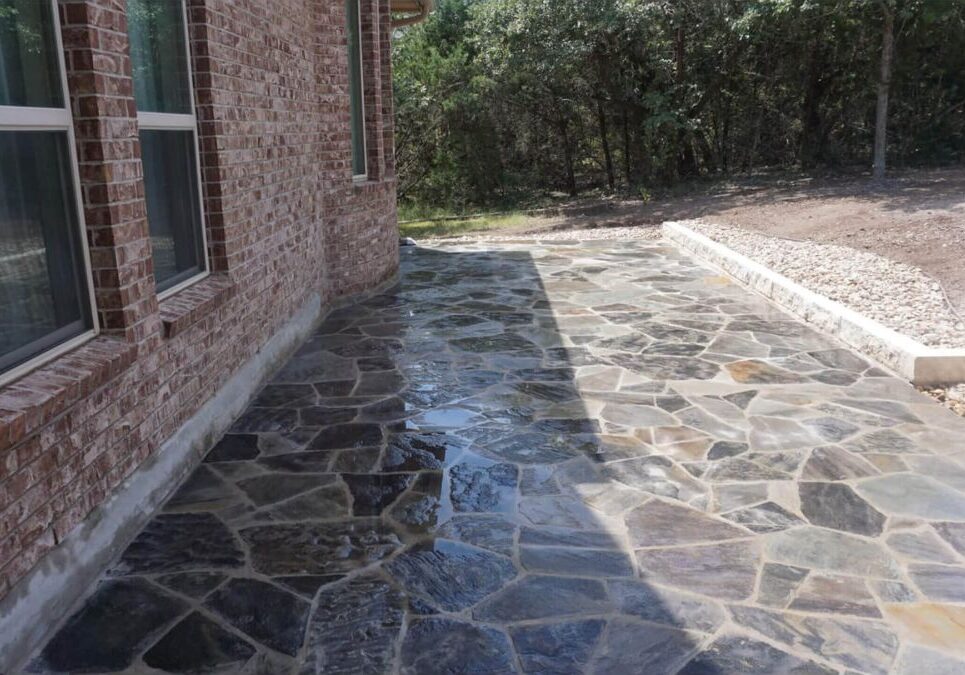 Natural stone patio installation alongside brick home in Austin, TX