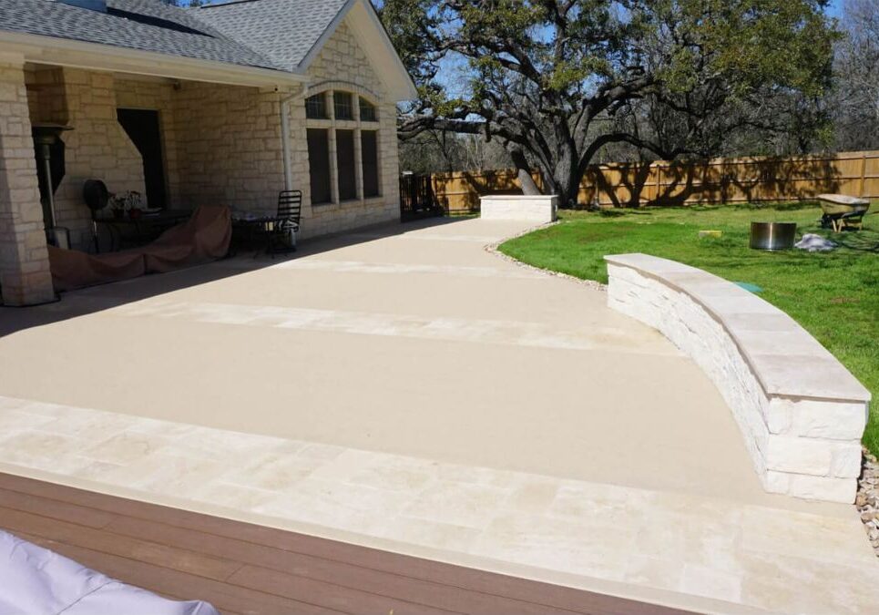 Custom stone patio with curved seating wall in Austin, TX backyard